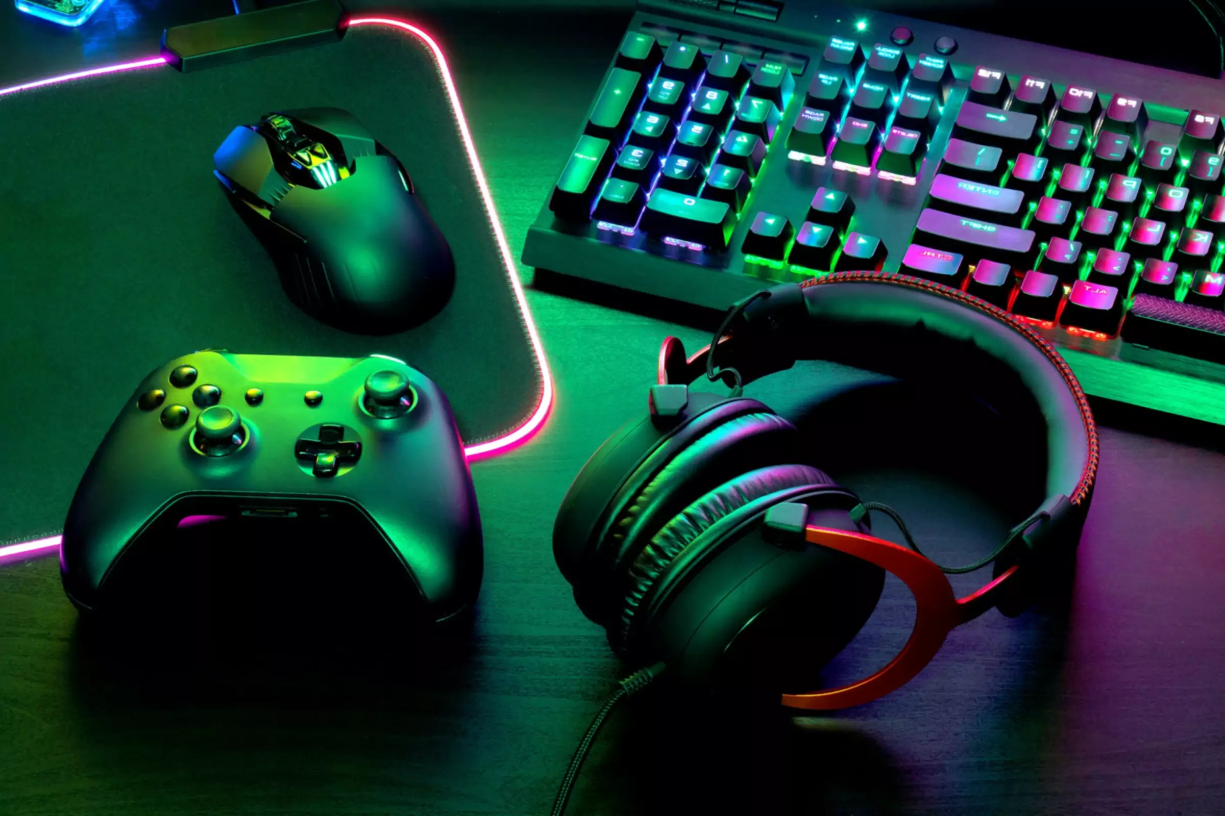 Controller di gioco accanto alla tastiera Mouse e tastiera illuminati con luci verdi e viola