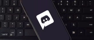 Viedtālrunis ar Discord lietotnes logotipu, kas atrodas uz tastatūras