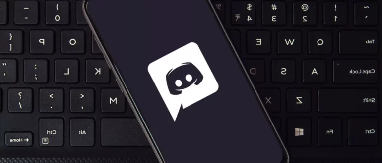 Smartphone care afișează logo-ul aplicației Discord așezat pe tastatură