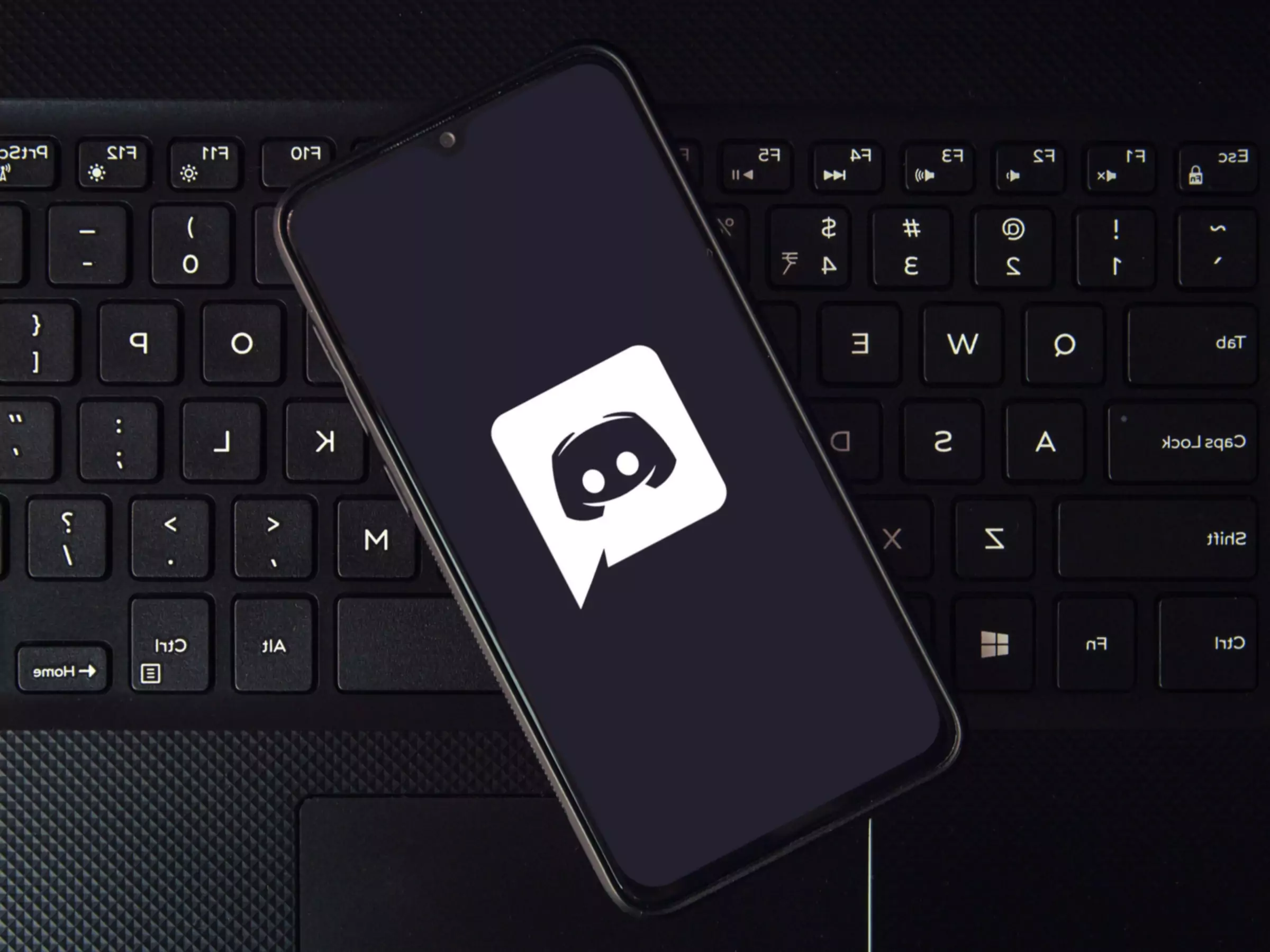 Viedtālrunis ar Discord lietotnes logotipu, kas atrodas uz tastatūras