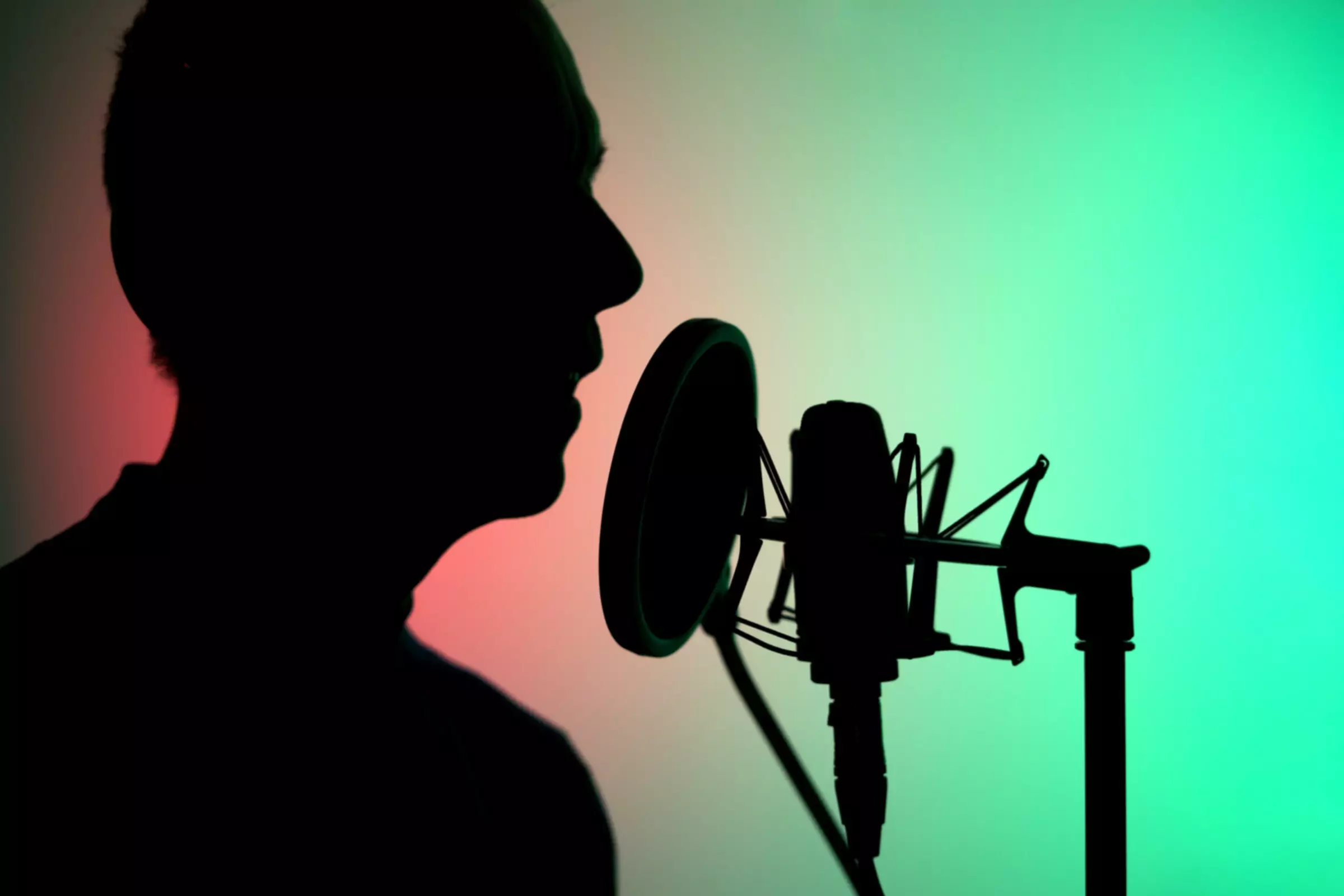 Una persona in silhouette che parla al microfono di uno studio