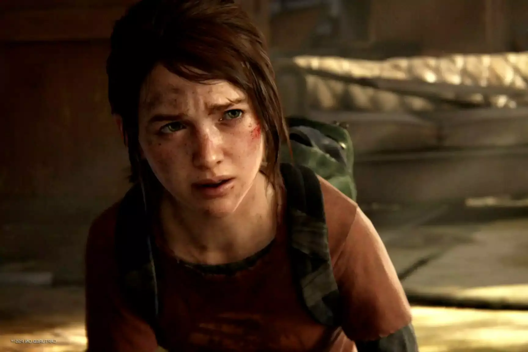 Screenshot z The Last of Us Part 1 Remastered s postavou s řeznými ranami a modřinami, která vypadá vyděšeně
