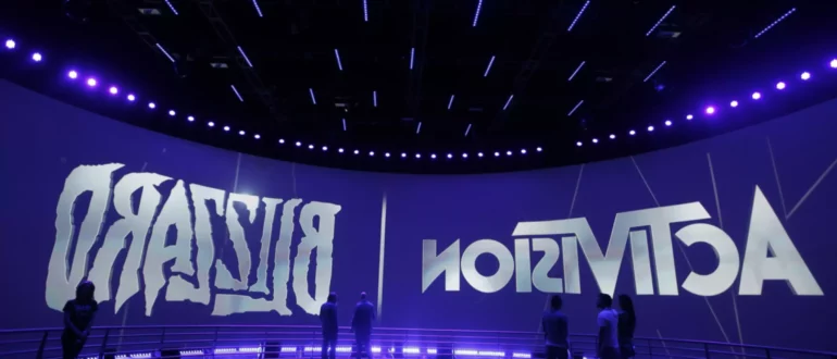 Ljudje stojijo okoli logotipov Activision Blizzard na velikem zaslonu